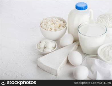 Fresh dairy products on white background. Glass of milk, bowl of sour cream, cottage cheese and baking flour and mozzarella. Eggs and cheese.