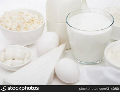 Fresh dairy products on white background. Glass of milk, bowl of sour cream, cottage cheese and baking flour and mozzarella. Eggs and cheese.