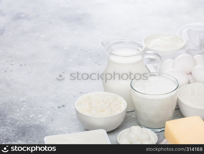 Fresh dairy products on white background. Jar and glass of milk, bowl of sour cream, cottage cheese and baking flour and mozzarella. Eggs and cheese.