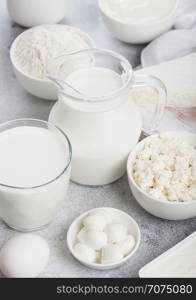 Fresh dairy products on white background. Jar and glass of milk, bowl of sour cream, cottage cheese and baking flour and mozzarella. Eggs and cheese.