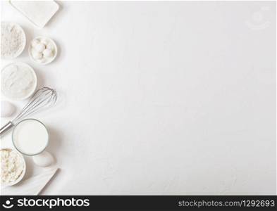 Fresh dairy products on white table background. Glass of milk, bowl of flour, sour cream and cottage cheese and eggs. Steel whisk