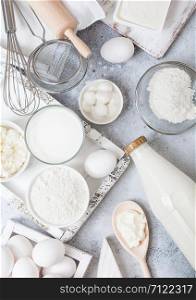 Fresh dairy products on white table background. Glass of milk, bowl of flour and cottage cheese and eggs. Box of baking utensils. whisk and spatula in vintage wooden box.