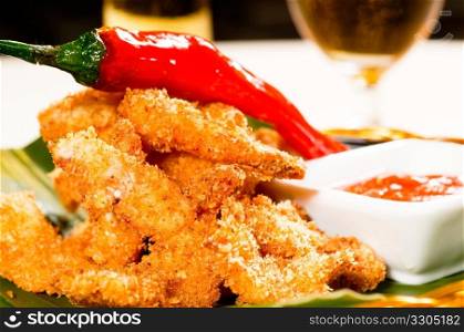 fresh deep fried buffalo shrimps with a red chili pepper on top and sweet and sour sauce dip on side