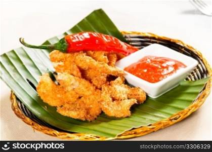 fresh deep fried buffalo shrimps with a red chili pepper on top and sweet and sour sauce dip on side