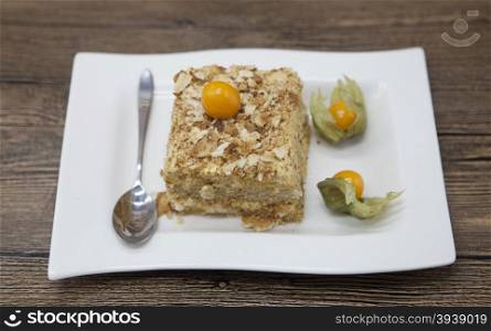 Fresh delicious diet cake with berry Physalis at Dukan Diet on a porcelain plate with a spoon on a wooden background.. Fresh delicious diet cake with berry Physalis at Dukan Diet on a porcelain plate with a spoon on a wooden background