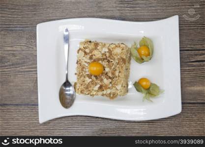 Fresh delicious diet cake with berry Physalis at Dukan Diet on a porcelain plate with a spoon on a wooden background.. Fresh delicious diet cake with berry Physalis at Dukan Diet on a porcelain plate with a spoon on a wooden background