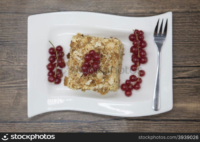 Fresh delicious diet cake with berry red currant at Dukan Diet on a porcelain plate with a spoon on a wooden background.. Fresh delicious diet cake with berry red currant at Dukan Diet on a porcelain plate with a spoon on a wooden background