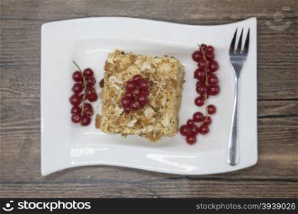Fresh delicious diet cake with berry red currant at Dukan Diet on a porcelain plate with a spoon on a wooden background.. Fresh delicious diet cake with berry red currant at Dukan Diet on a porcelain plate with a spoon on a wooden background