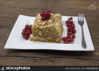 Fresh delicious diet cake with berry red currant at Dukan Diet on a porcelain plate with a spoon on a wooden background.. Fresh delicious diet cake with berry red currant at Dukan Diet on a porcelain plate with a spoon on a wooden background