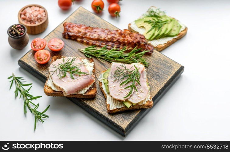 Fresh, delicious ham, butter, avocado and sesame seeds sandwiches on a wooden cutting board. Delicious healthy food. Fresh, delicious ham, butter, avocado and sesame seeds sandwiches on a wooden cutting board