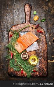 Fresh delicious salmon fillet with dill, oil and ingredients for cooking on rustic cutting board , wooden background, top view.