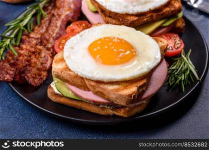 Fresh, delicious sandwiches with fried egg, ham, butter, avocado and sesame seeds on a wooden cutting board. Delicious hea<hy food. Fresh, delicious sandwiches with fried egg, ham, butter, avocado and sesame seeds