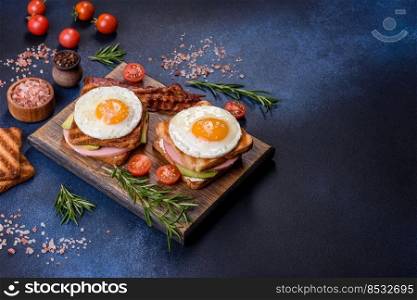 Fresh, delicious sandwiches with fried egg, ham, butter, avocado and sesame seeds on a wooden cutting board. Delicious healthy food. Fresh, delicious sandwiches with fried egg, ham, butter, avocado and sesame seeds