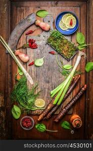 Fresh delicious seasoning and spices for healthy cooking around rustic cutting board on wooden background, top view. Clean food or vegetarian cooking concept
