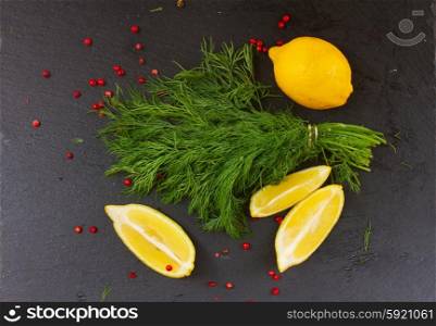 Fresh dill. Fresh green dill with red pepper spice and lemons on black board