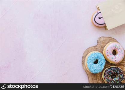 fresh donuts chopping board near package pink background