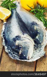 fresh dorada fish with thyme and lemon on wooden board - food and drink