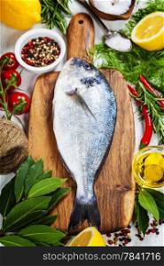 fresh dorado fish and vegetables on wooden board - food and drink