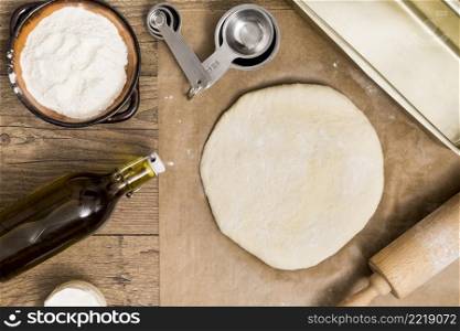 fresh dough ready baking parchment paper with measuring spoons flour oil rolling pin wooden desk