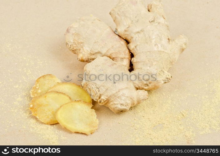 Fresh, dried and powdered ginger at brown background