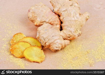 Fresh, dried and powdered ginger at brown background