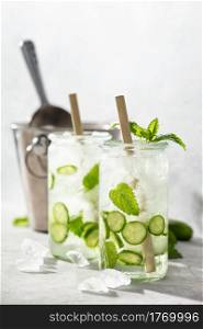 Fresh drinks with cucumber and mint, cold summer lemonade. Modern minimalism concept. Sunny day shadows. Delicious refreshing water with mint and cucumber, hard light and shadows