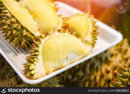 Fresh durian peeled on tray and ripe durian fruit on background for sale in the market