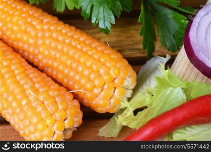 Fresh ear of corn with chuli pepper on wooden background