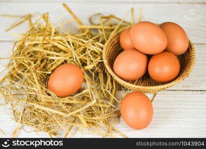 Fresh egg on basket and straw with wooden table background top view / Raw chicken eggs collect from the farm products natural eggs