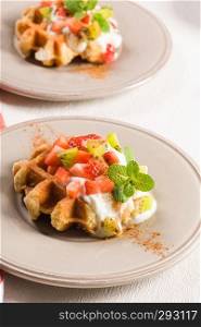 Fresh egg waffles dessert for breakfast with yogurt, strawberries and kiwi.