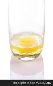 Fresh egg with yolk on transparent glass cup