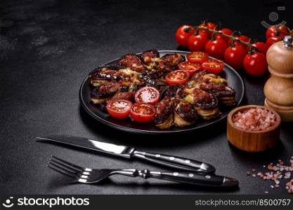 Fresh eggplant baked with minced meat, spices and herbs on a black plate against a dark concrete background. Fresh eggplant baked with minced meat, spices and herbs on a black plate