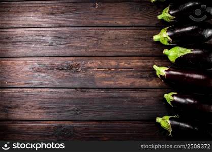 Fresh eggplants are in a row on the table. On a wooden background. High quality photo. Fresh eggplants are in a row on the table. 