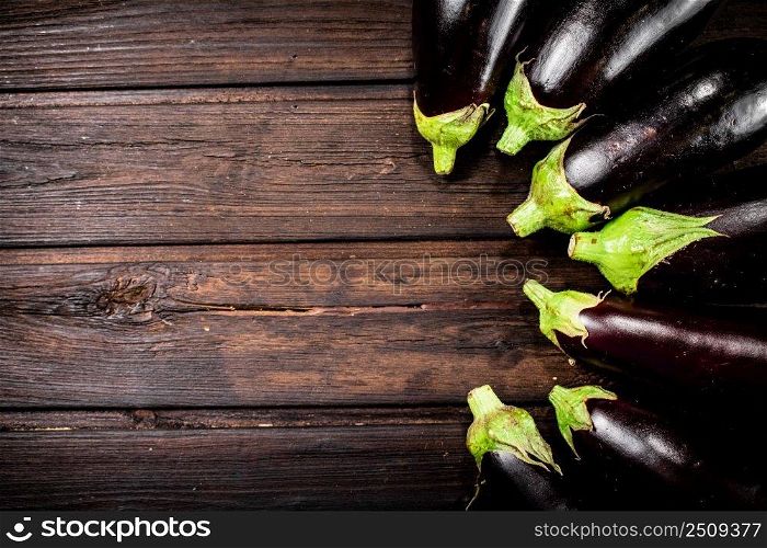Fresh eggplants are in a row on the table. On a wooden background. High quality photo. Fresh eggplants are in a row on the table. 