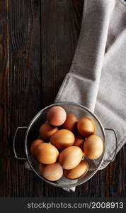 fresh eggs in a basket on wooden table.. fresh eggs in metal basket on wooden table.