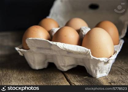 Fresh eggs in egg box in moody natural lighting vintage style set up