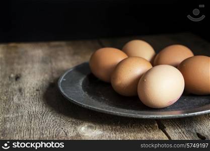Fresh eggs on pewter plate in vintage style natural lighting set up