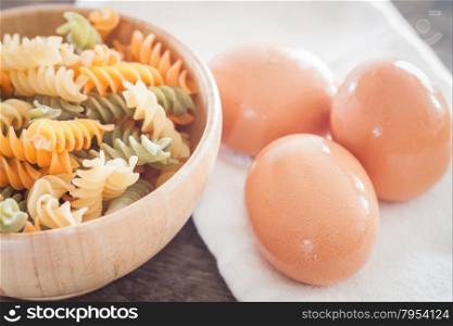Fresh eggs on wooden plate with fusili , stock photo