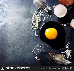 Fresh eggs with straw and feathers on a dark background