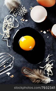 Fresh eggs with straw and feathers on a dark background