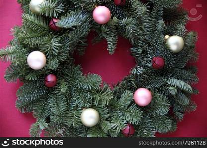 fresh evergreen wreath with pastel ornaments and red jingle bells