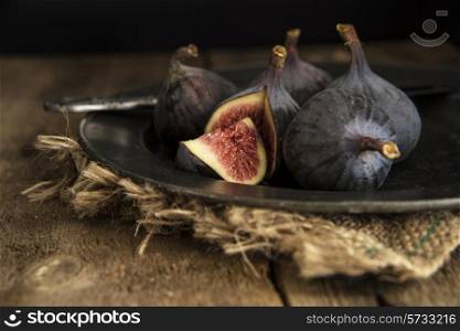 Fresh figs in moody natural lighting set with vintage style. food, fresh, raw, fruit, vegetables, wood, wooden, background, grunge, retro, vintage, moody, dark,