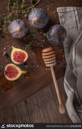 Fresh figs. Whole figs and sliced in half figs and thyme leaves on wooden cutting board. Flat layer.