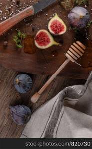 Fresh figs. Whole figs and sliced in half figs and thyme leaves on wooden cutting board