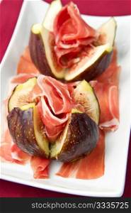 Fresh figs with ham on a white plate