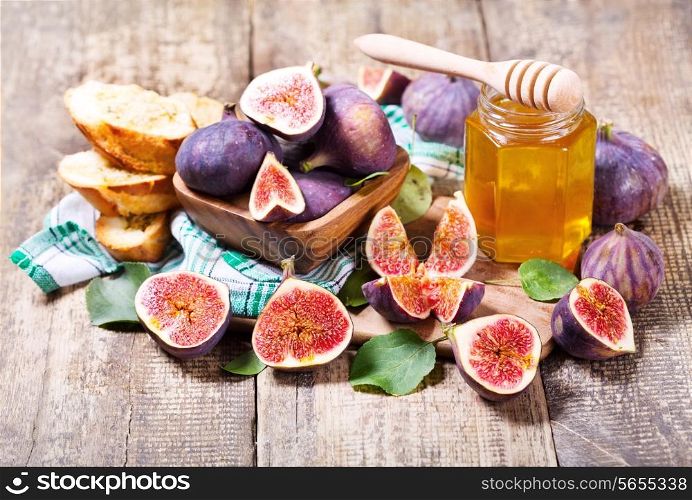 fresh figs with jar of honey on wooden table
