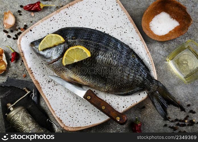 Fresh fish dorado. Dorado and ingredients for cooking at black slate table. Top view with copy space.