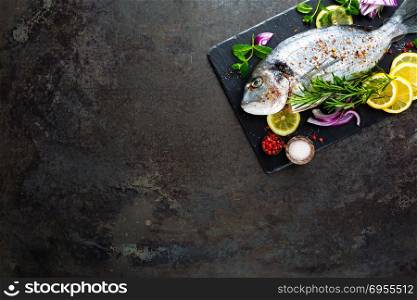 Fresh fish dorado. Raw dorado fish and ingredient for cooking on board. Sea bream or dorada fish on kitchen table