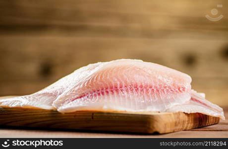 Fresh fish fillet on a cutting board. On a wooden background. High quality photo. Fresh fish fillet on a cutting board.