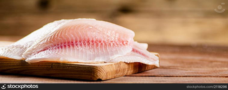 Fresh fish fillet on a cutting board. On a wooden background. High quality photo. Fresh fish fillet on a cutting board.